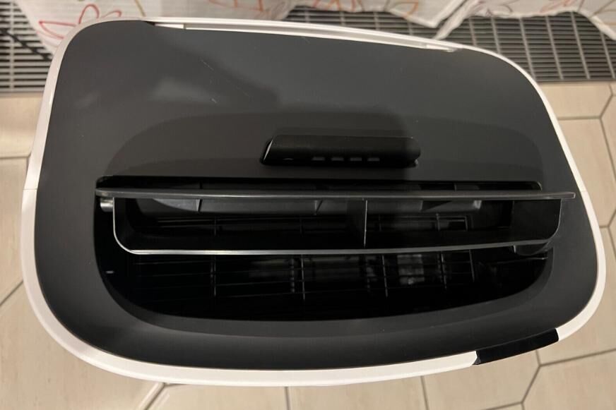 Die Fernbedienung einer De’Longhi mobilen Klimaanlage ist im Fach der Klimaanlage eingesteckt..